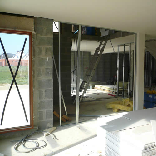 Pose de l'ossature métallique des plaques de plâtre dans une maison en travaux.